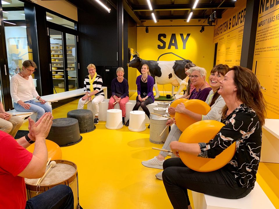Groep dames doet aan kaasdrummen in het Kaaspakhuis Woerden – een ludieke en Hollandse groepsactiviteit midden in het Groene Hart.