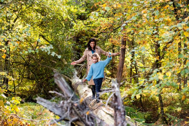 Moeder en kind op boomstam in herfstbos