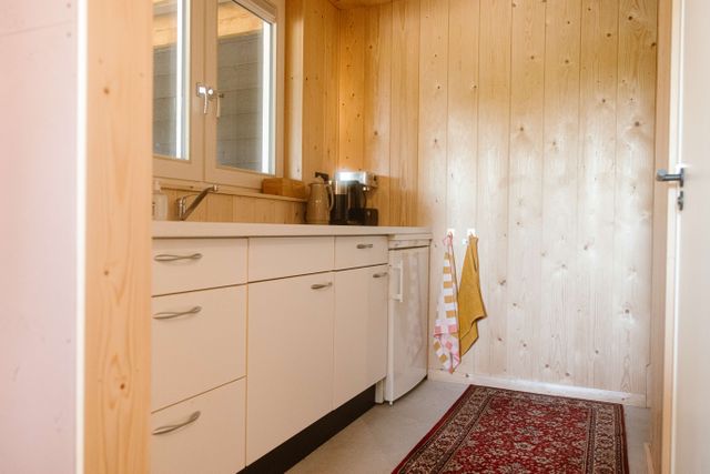 Keuken van Aliedas Annex bij Esti Yoga in Lopik, Groene Hart, met lichte houten wandbekleding, witte keukenkasten, koffiezetapparaat en koelkast.