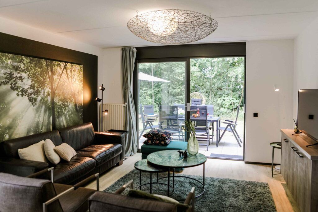 Lichte woonkamer met schuifpui naar het terras en de groene, volledig omheinde privétuin.