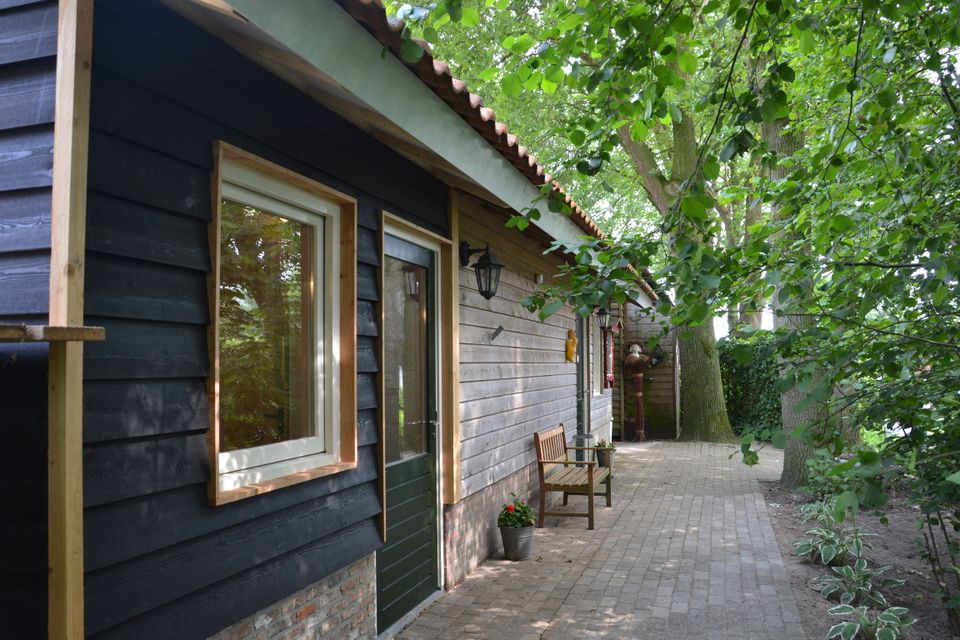 Foto van een houten bijgebouw tussen de bomen.