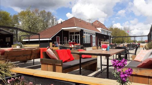 Foto met restaurant, houten bankjes en oranje kussens