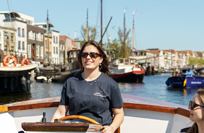 Meisje aan het stuur in een boot in de Leidse grachten aan het varen