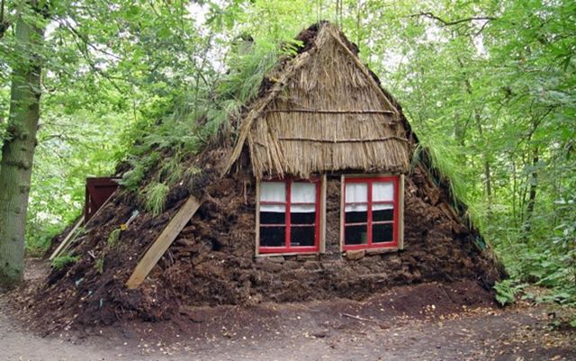 Een plaggenhut tussen de bomen.