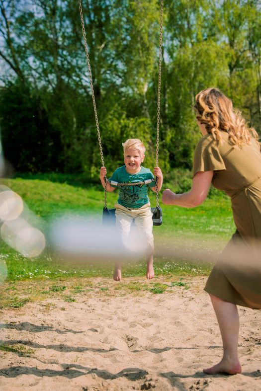 Jongen zit lachend een schommel.