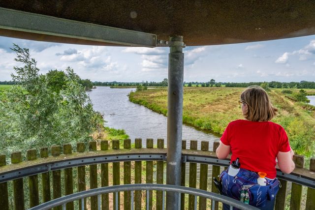 Wandelboswachter Ellen kijkt uit over de Hollandse IJssel vanuit een uitkijktoren