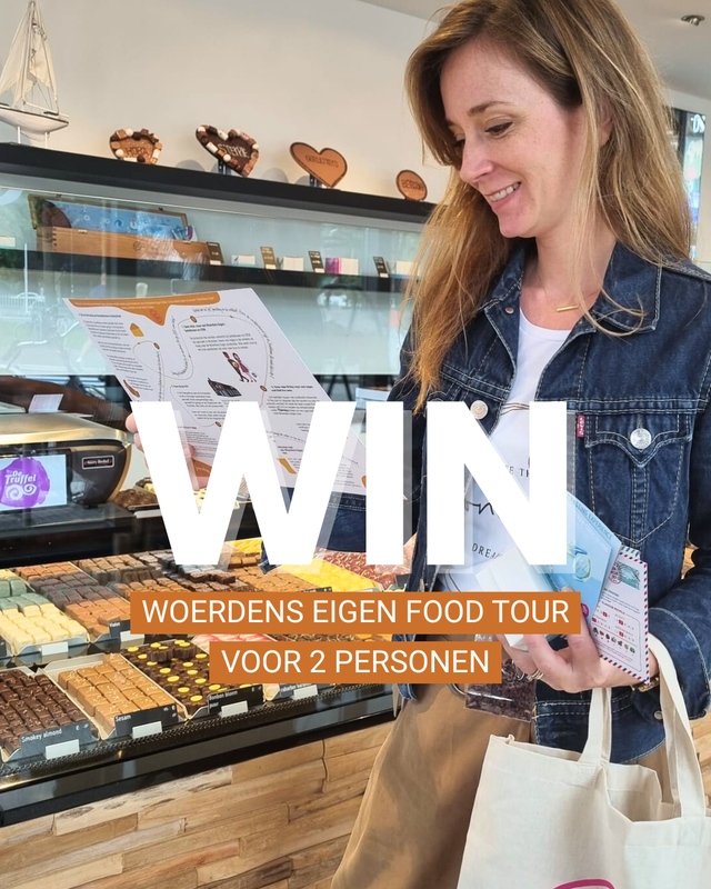 Vrouw met een tas van ‘Woerdens Eigen’ bekijkt de routekaart van de Woerdens Eigen Food Tour in chocolaterie Choco Made Woerden, met op de achtergrond een vitrine vol kleurrijke bonbons en chocolade.