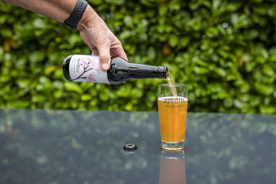 Iemand schenkt een flesje drinken leeg in een glas