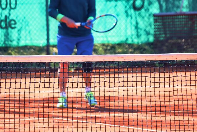 Tennis - close-up van het net met op de achtergrond een tennisser