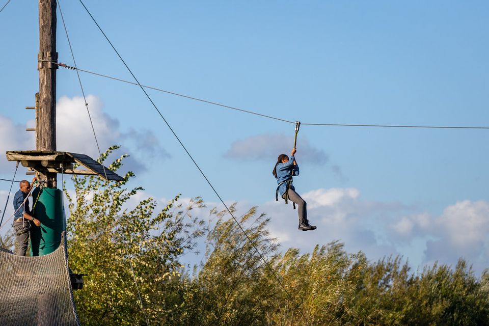 Personen gaan met de zipline vanaf de uitkijktoren bij De Reuselhoeve naar beneden