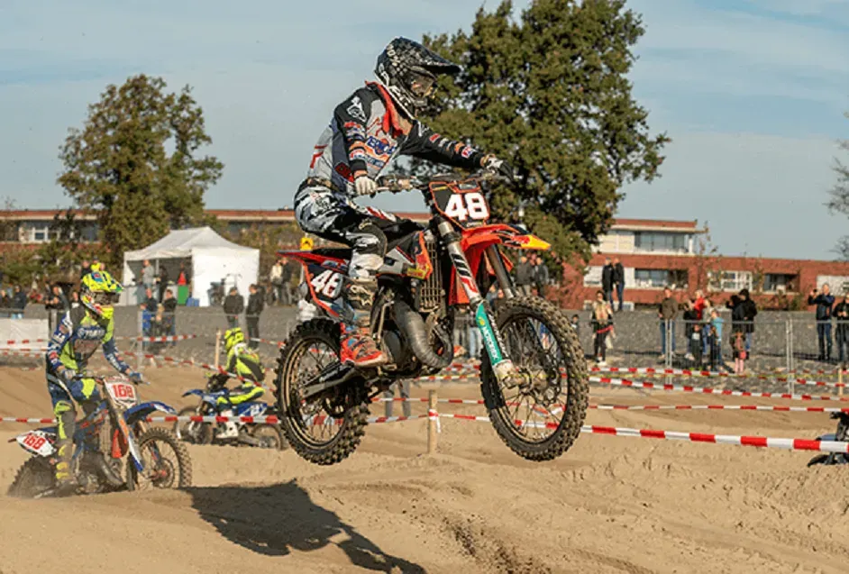 Een motorcrosser die een sprong maakt op een parcours op het strand.