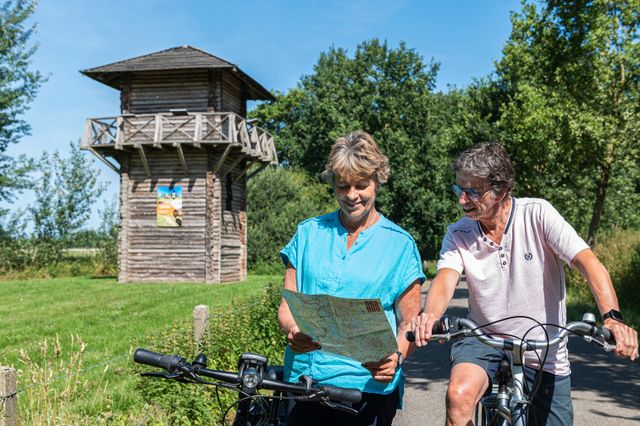 Fietsers bekijken een routekaart naast de wachttoren van Castellum Fectio.