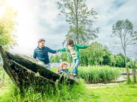 Gezin klimt op rots in de natuur van Almere.