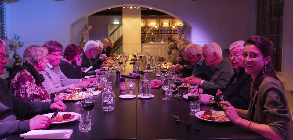 Gezamenlijk diner Café Woerden Fotografen, gasten aan lange tafel in restaurant in Woerden, Groene Hart, sfeervolle binnenruimte met gedeelde maaltijd en ontmoeting tijdens een culturele avond.
